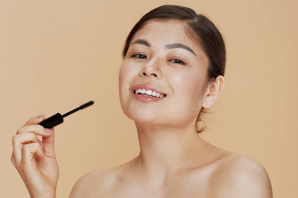 istock young woman with mascara isolated on beige background 1809571349