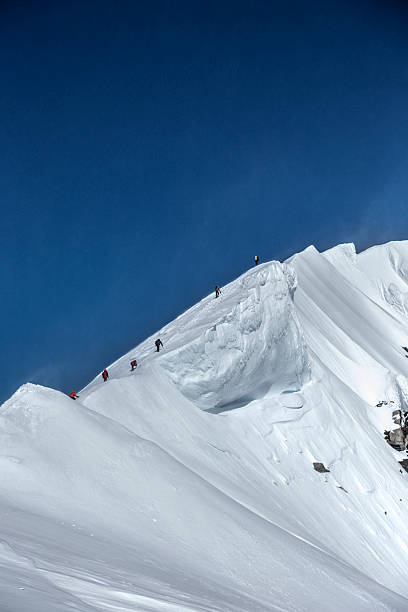 Mountaineers climbing a snowy ridge