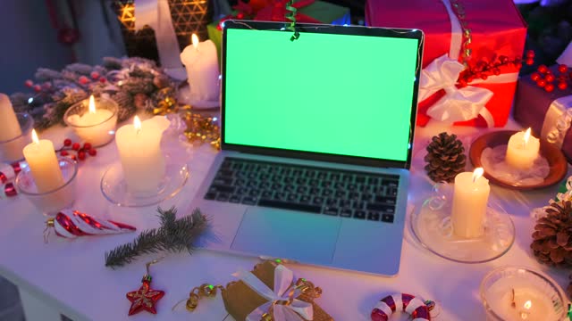 Close up laptop computer with chromakey screen on white table among wrapped Christmas presents