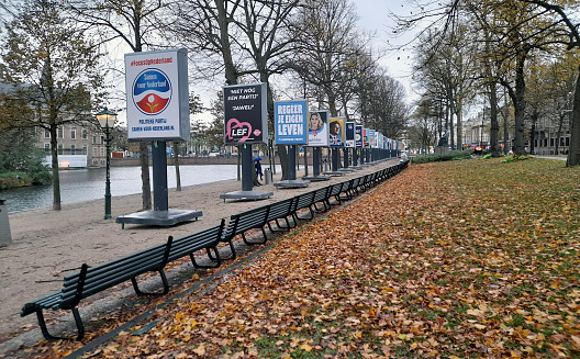 The Hague, Netherlands - November 8, 2023: Dutch Parliament Building Exterior, People Walking Around,  Dutch House Of Representatives Early General Elections Poster, Water, Tree Scene During Autumn Season