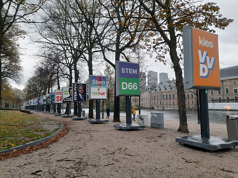 The Hague, Netherlands - November 8, 2023: Dutch Parliament Building Exterior, People Walking Around,  Dutch House Of Representatives Early General Elections Poster, Water, Tree Scene During Autumn Season