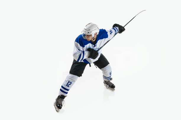Man, ice hockey player in motion during game with stick, training, playing against white studio background. Concept of professional sport, competition, game, tournament, game, action