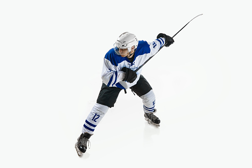 Man, ice hockey player in motion during game with stick, training, playing against white studio background. Concept of professional sport, competition, game, tournament, game, action