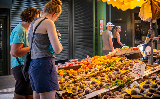 Two people looking at a display of fresh figs for sale on a market stall in Borough Market in Southwark, South East London.