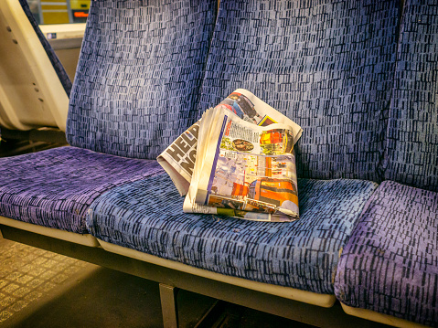 An old, rumpled, discarded newspaper on a seat in a railway carriage.