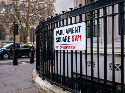 Street sign on a corner of Parliament Square in the City of Westminster, London. Westminster Abbey is in the background.