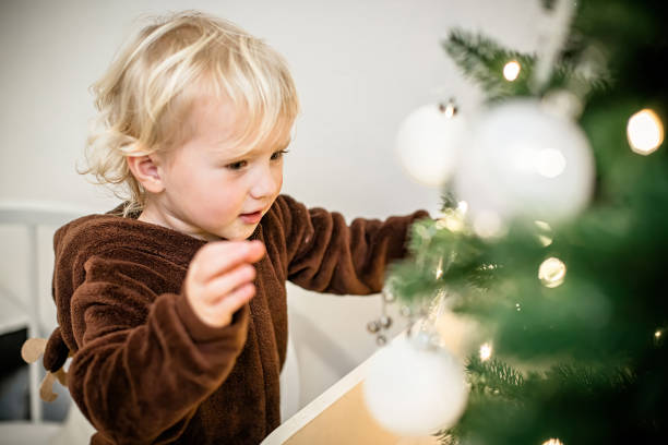 istock Cute little boy decorating christmas tree with baubles 1809621685