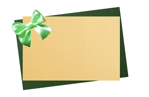 Gift two-color card. Gold blank card on green. Green satin bow. Isolated on a white background. Copy space. Christmas, Easter or St. Patrick day present template mockup