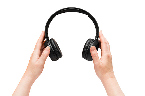 Hands holding big black headphones on isolated white background. View from above.