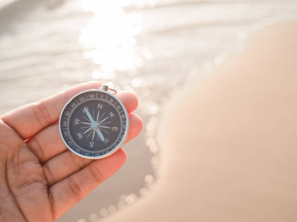 istock Close up hand holding compass with beach background 1809632806