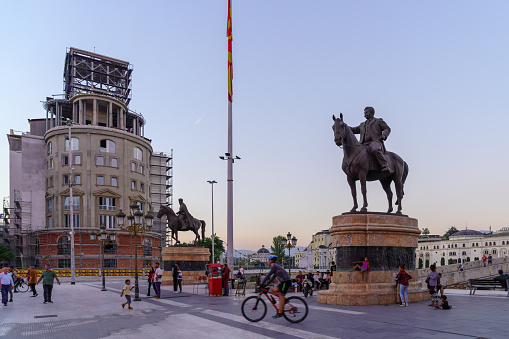 Skopje, North Macedonia - October 04, 2023: Sunset scene of the Macedonia Square, with various monuments, locals, and visitors, in Skopje, North Macedonia