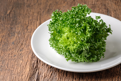 Photo Image of Frillice Iceberg Lettuce on white plate, with wooden table, Copy space for your text.