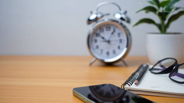 istock Office table of modern workplace with notebooks and pencils, phone, clock on wooden table. side view and copy space on wooden floor, Flat lay, side view office table with glasses. 1809652552