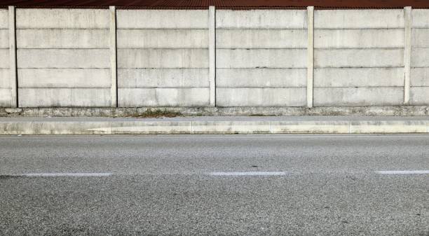 istock Grunge concrete precast compound wall at the road side with cement sidewalk and road in front. 1809659610