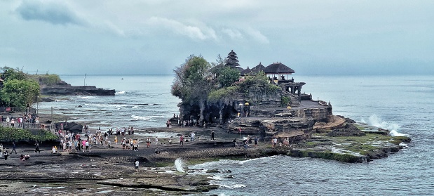 Tanah Lot, Bali, Indonesia - Nov 19, 2023: People came to Pura Tanah Lot Bali for vacation and praying Hinduism religion with open sea and blue sky as the background
