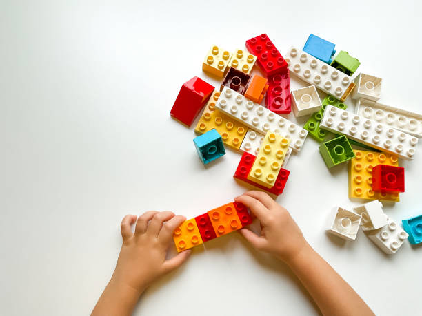 istock Child playing with colorful building blocks on white background. Top view 1809671310