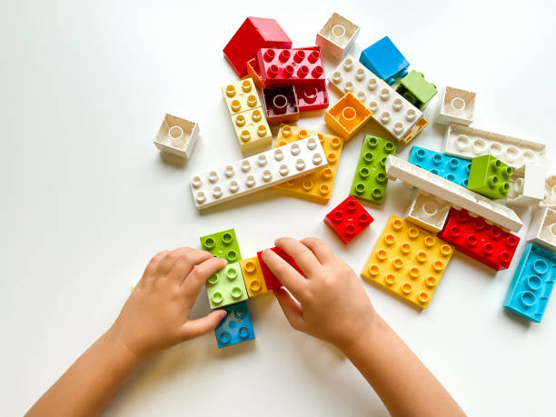 istock Child playing with colorful building blocks on white background. Top view 1809672453