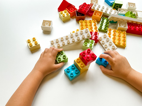 Child playing with colorful building blocks on white background. Top view. High quality photo
