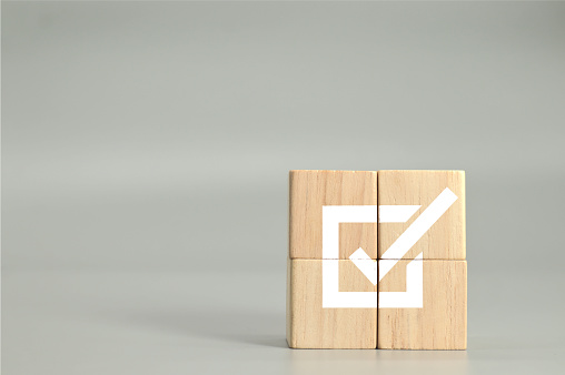 wooden cubes with checkmark icon on gray background, business success.task completion. Ethical corporate. Do the right thing. Quality and ISO symbol.