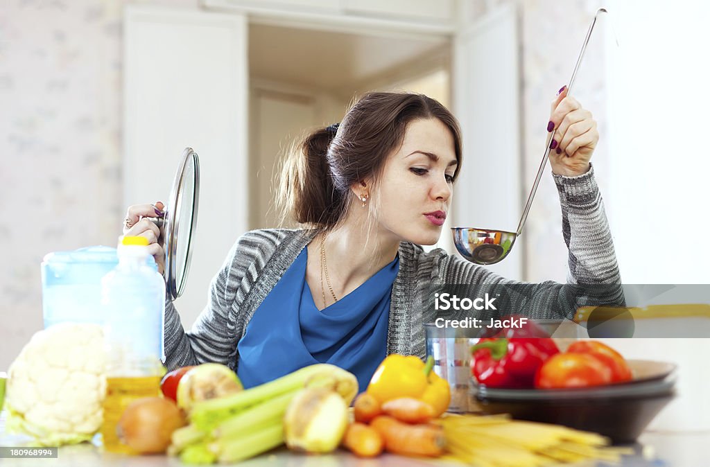 young woman tests food young woman tests food with ladle in the kitchen at home Beautiful Woman Stock Photo