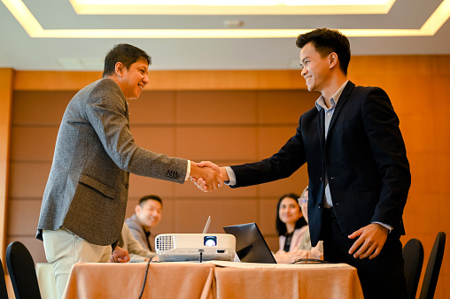 Young asian businessman shaking hand with partner