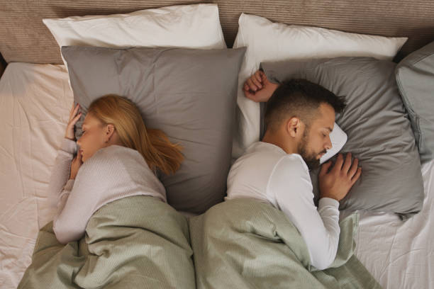młoda para śpiąca w łóżku plecami do siebie - sleeping lying on back couple bed zdjęcia i obrazy z banku zdjęć