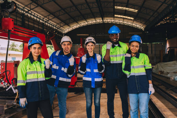 istock A diverse group of engineers and workers wearing life jackets and helmets join hands together as a working team in an industrial plant and machining. 1809697855