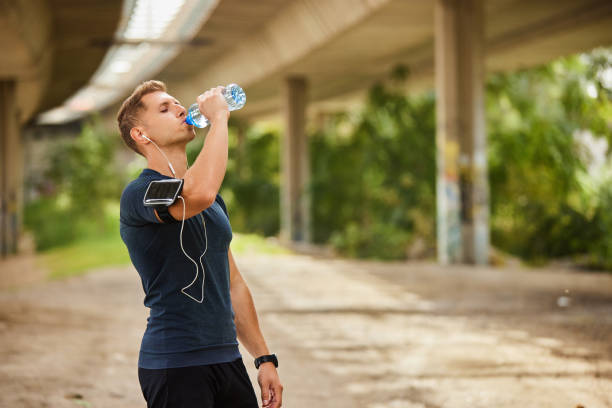istock Male runner under bridge in the city drinking water 1809700555