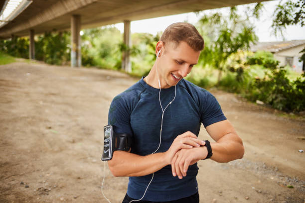 istock Male athlete looking at his smart watch or tracker under bridge 1809702812