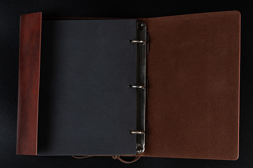 Open notebook in leather cover with black pages in binder above top view