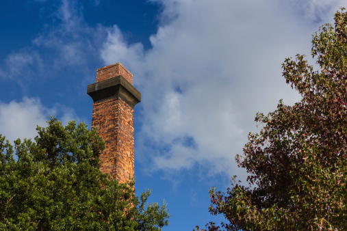 Old brick chimney with a bright blue sky background.