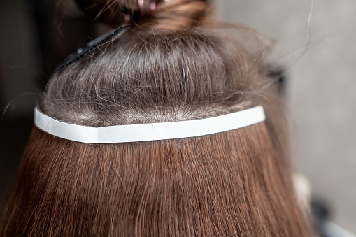 Hair ribbons for extensions on a woman's head at home.