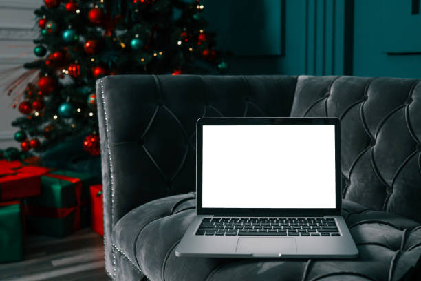 istock Laptop with blank screen on a desktop and Christmas tree with lights in the background 1809764182