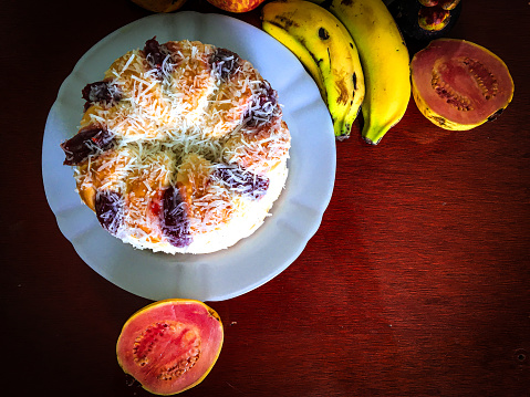 A beautiful and tasty sweet homemade bread with guava filling and covered with grated coconut on the rustic wooden board