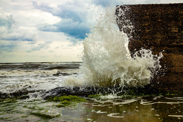 Wave breaks against wall on the beach In some areas of the Emerald Coast in Veracruz, Mexico, the sea has reached buildings that face the force of the sea. Here a wave breaks violently against a wall already degraded by the waves. costa esmeralda stock pictures, royalty-free photos & images