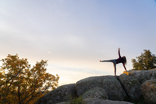 Woman practicing yoga at sunrise in nature