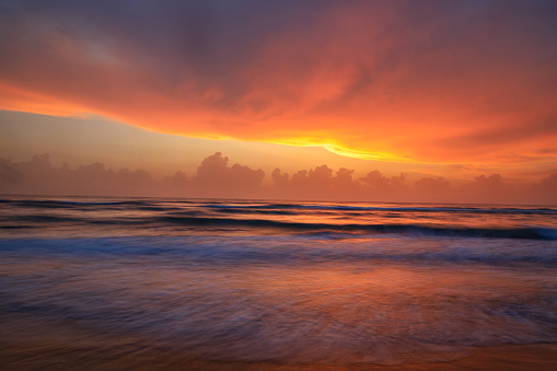A sunrise painted pink, where you can see the first rays of the sun touching the clouds over the Gulf of Mexico.