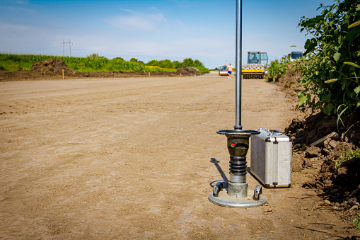 Instrument, device for measuring hardness of road base compaction and metal waterproof hard case placed on the ground. Surveying equipment at the construction site