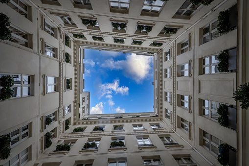 View from below of a geometric stone building and blue sky in an inner courtyard