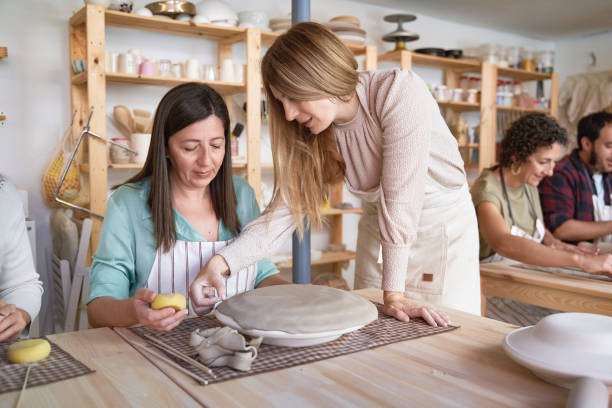 istock Potter woman helping her student in the ceramic workshop. 1809811871