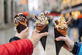 Three people holding Chimney cakes in downtown Budapest