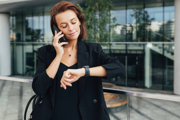 istock Middle-aged businesswoman looking at her smartwatch while talking on mobile phone 1809866609