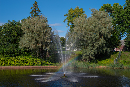 Beautiful landscape - rainbow in a fountain in the middle of the pond in the Valli park the Pärnu city centre on a sunny summer day.