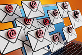 Email sign on an envelop floating in front of a laptop having blue screen on orange background. Illustration of the concept of office workload, email spam, phishing and scams
