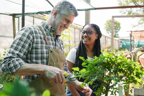 Senior Gardener with Young African Apprentice Enjoying Horticulture