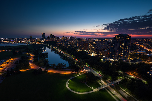 Aerial shot of Milwaukee, Wisconsin at twilight on a colorful Fall evening, flying over Veterans Park and looking towards apartment buildings on the Lower East Side and Yankee Hill and the downtown office buildings of Juneau Town.