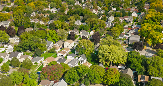 Drone shot of leafy residential streets and single family homes in Bluemound Heights, a neighborhood on the west side of Milwaukee, Wisconsin on a sunny day in Fall.