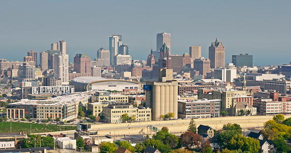 Aerial shot of Milwaukee, Wisconsin on a hazy day in Fall, looking across King Park and Interstate 43 towards the downtown skyline, with Lake Michigan in the distance.