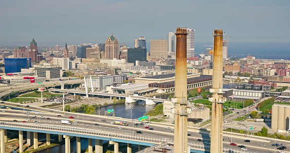 Aerial shot of downtown Milwaukee, Wisconsin on a hazy afternoon in Fall, looking past power plant chimneys and the Marquette Interchange where I-44, I-94 and I-794 meet towards Milwaukee Intermodal Station and Westown.  

Authorization was obtained from the FAA for this operation in restricted airspace.