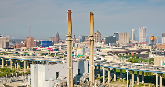 Aerial shot of downtown Milwaukee, Wisconsin on a hazy afternoon in Fall, looking past power plant chimneys and the Marquette Interchange where I-44, I-94 and I-794 meet towards Milwaukee Intermodal Station and Westown.  \n\nAuthorization was obtained from the FAA for this operation in restricted airspace.